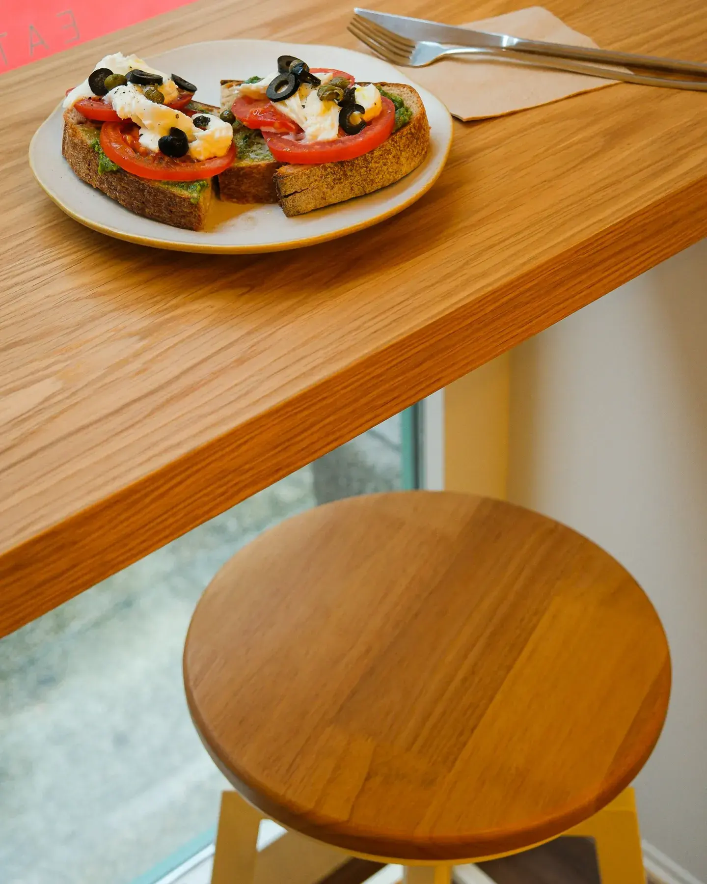 Um prato de torrada com tomate, ervas e azeitonas sobre uma mesa.